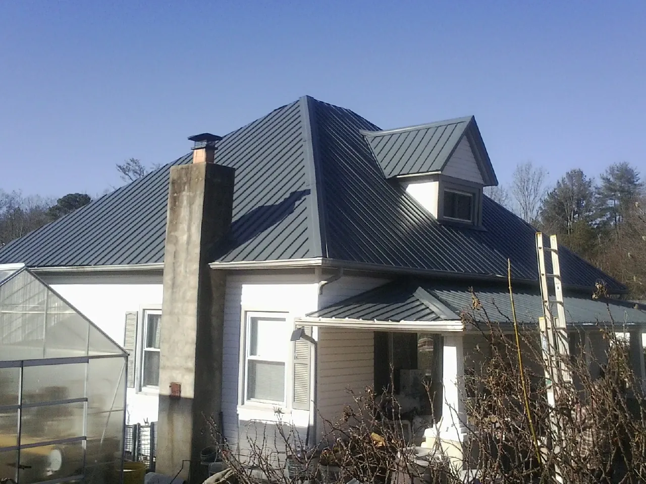 Dark blue standing seam metal roof on a white farmhouse with dormer — Slate & Tile Roof Repair by Roofing Brothers in Simsbury