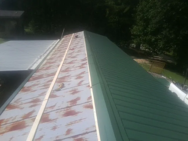 Old rusted panels beside newly installed green metal roofing — Wind Damage Roof Repair by Roofing Brothers in Simsbury