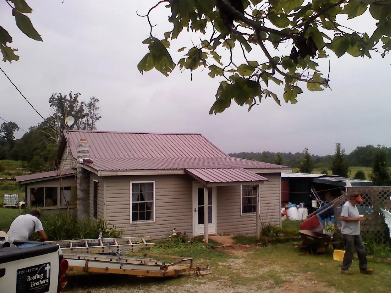Crew finishing a mauve metal roof on a small farmhouse in Simsbury