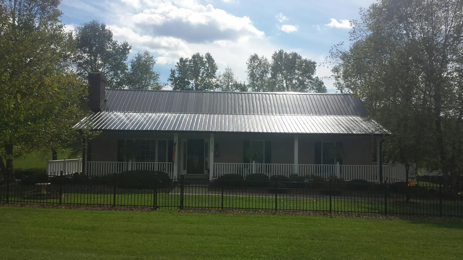 Gray metal roof on a brick ranch with a full width front porch — Gutter Guard Installation work by our crew in Simsbury