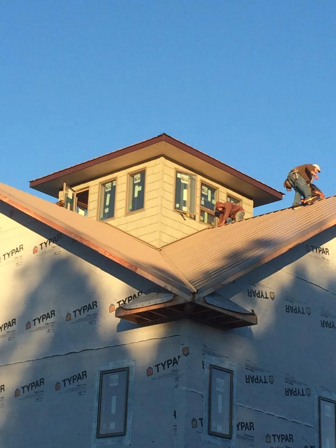 Roofers working around a rooftop cupola on a new metal roof at sunset — Roof Waterproofing in Simsbury by Roofing Brothers